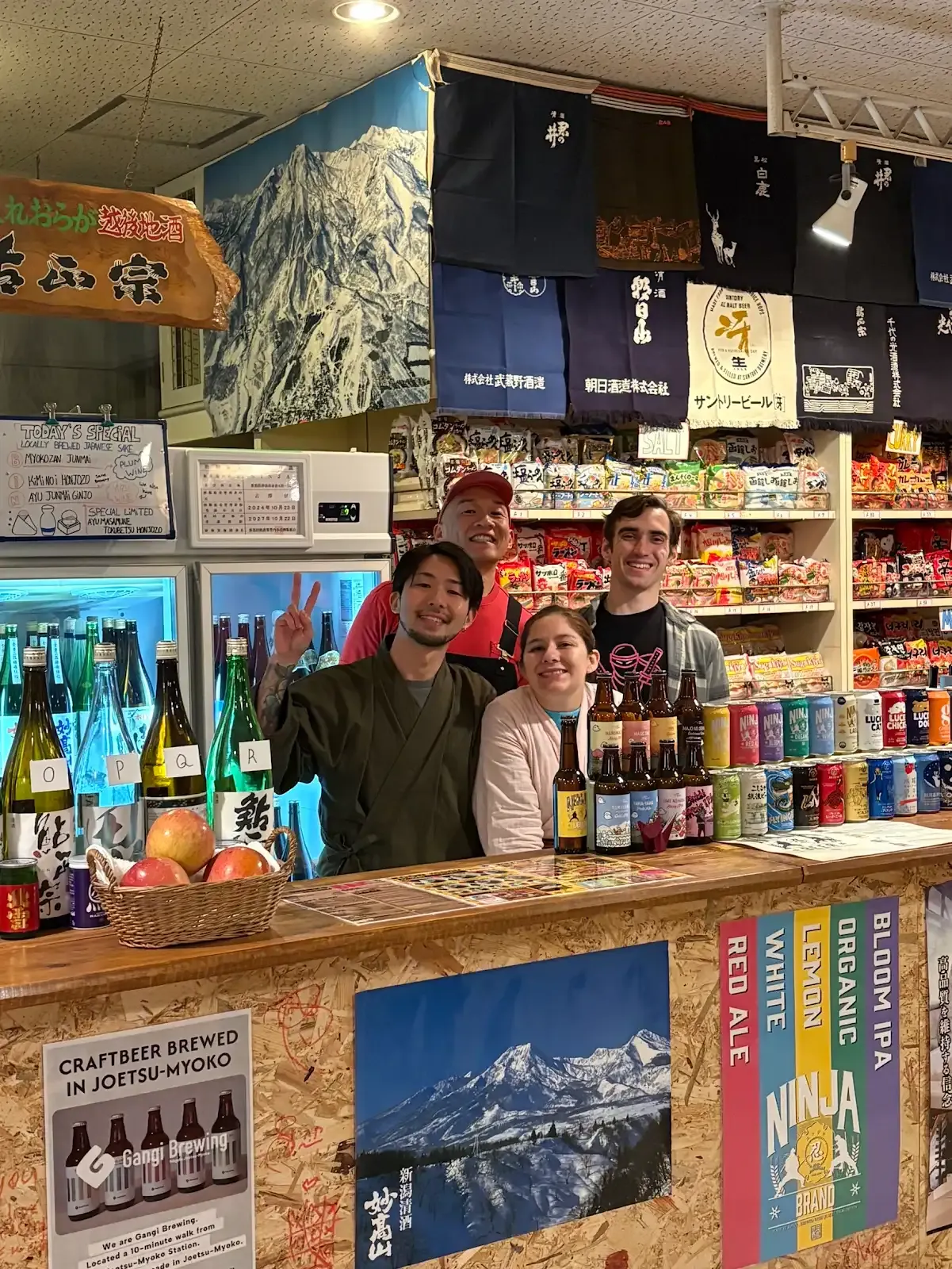 A group smiling behind the sake counter at NINJA