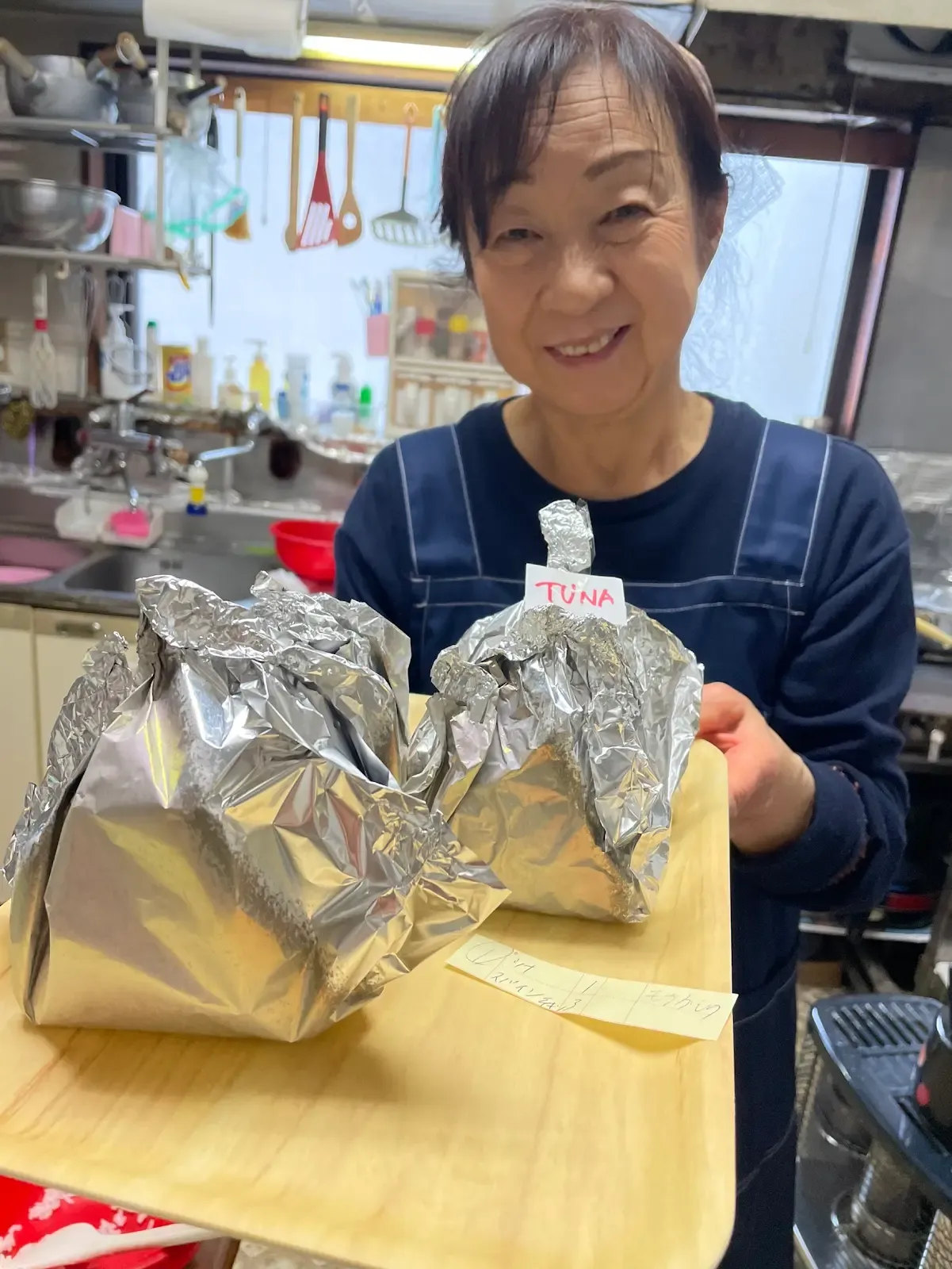 A smiling member of the NINJA team holding freshly prepared onigiri
